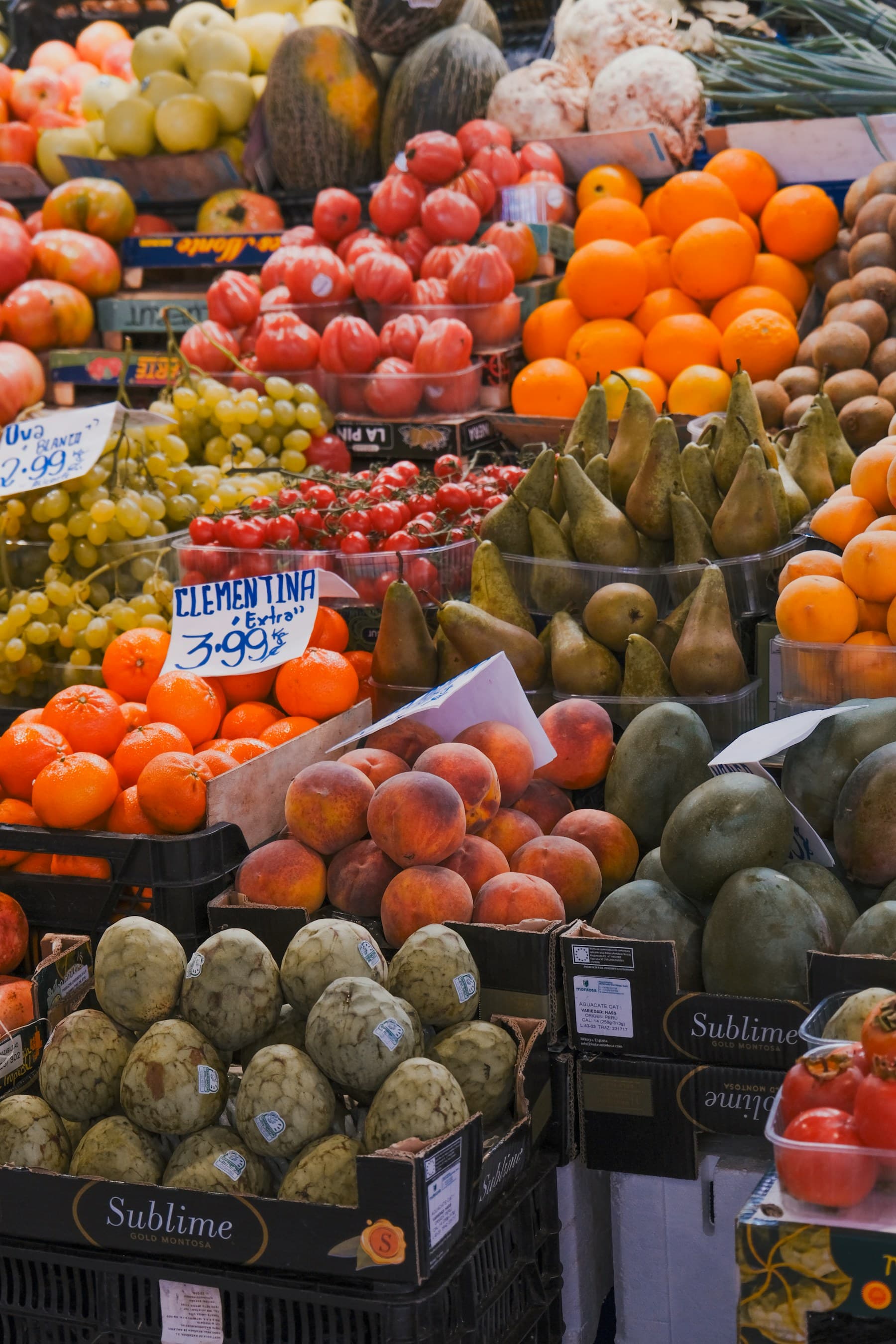 A fruit stall at La Boqueria, oranges and melons stacked under the market lights