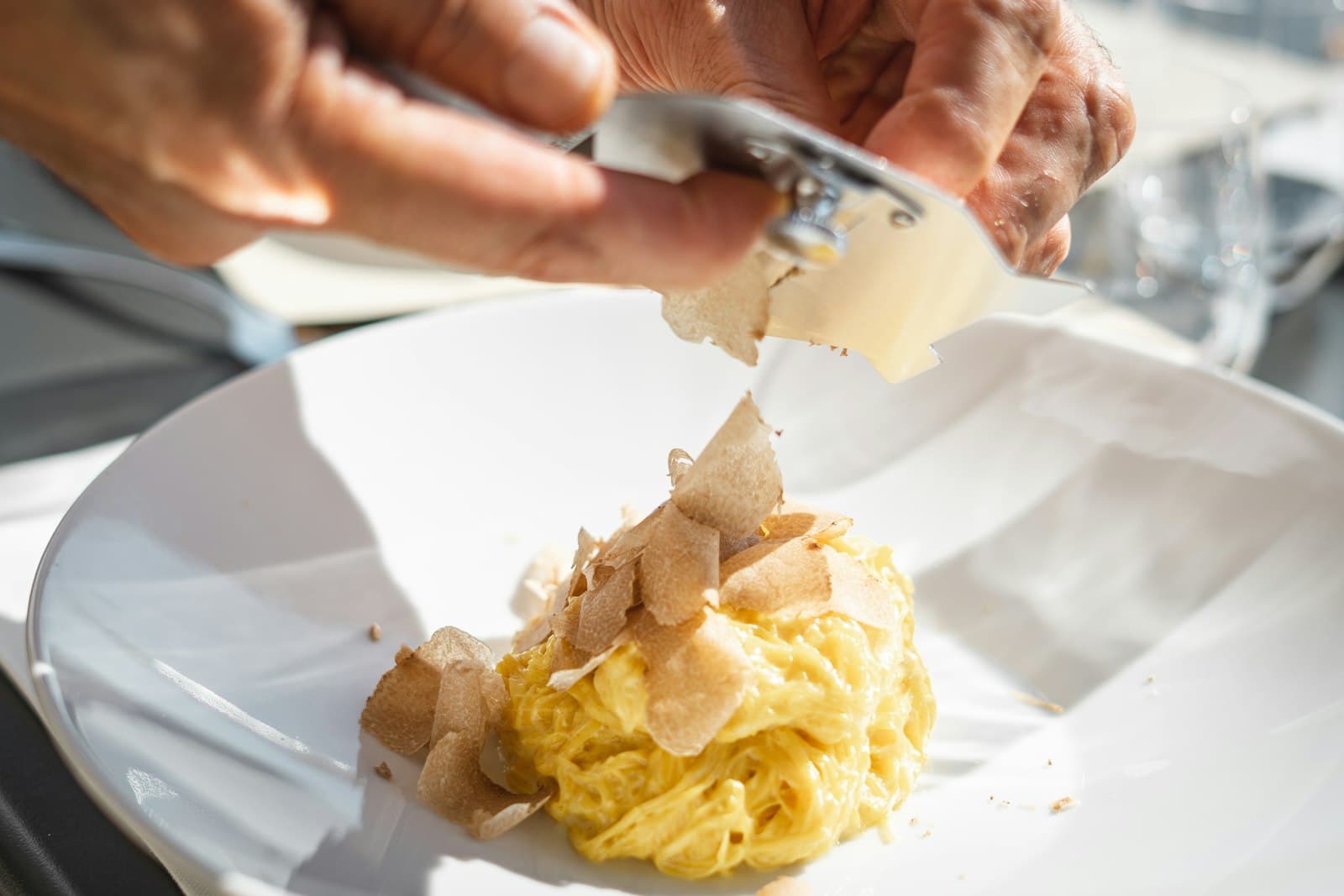 White truffle being shaved over a plate of tajarin