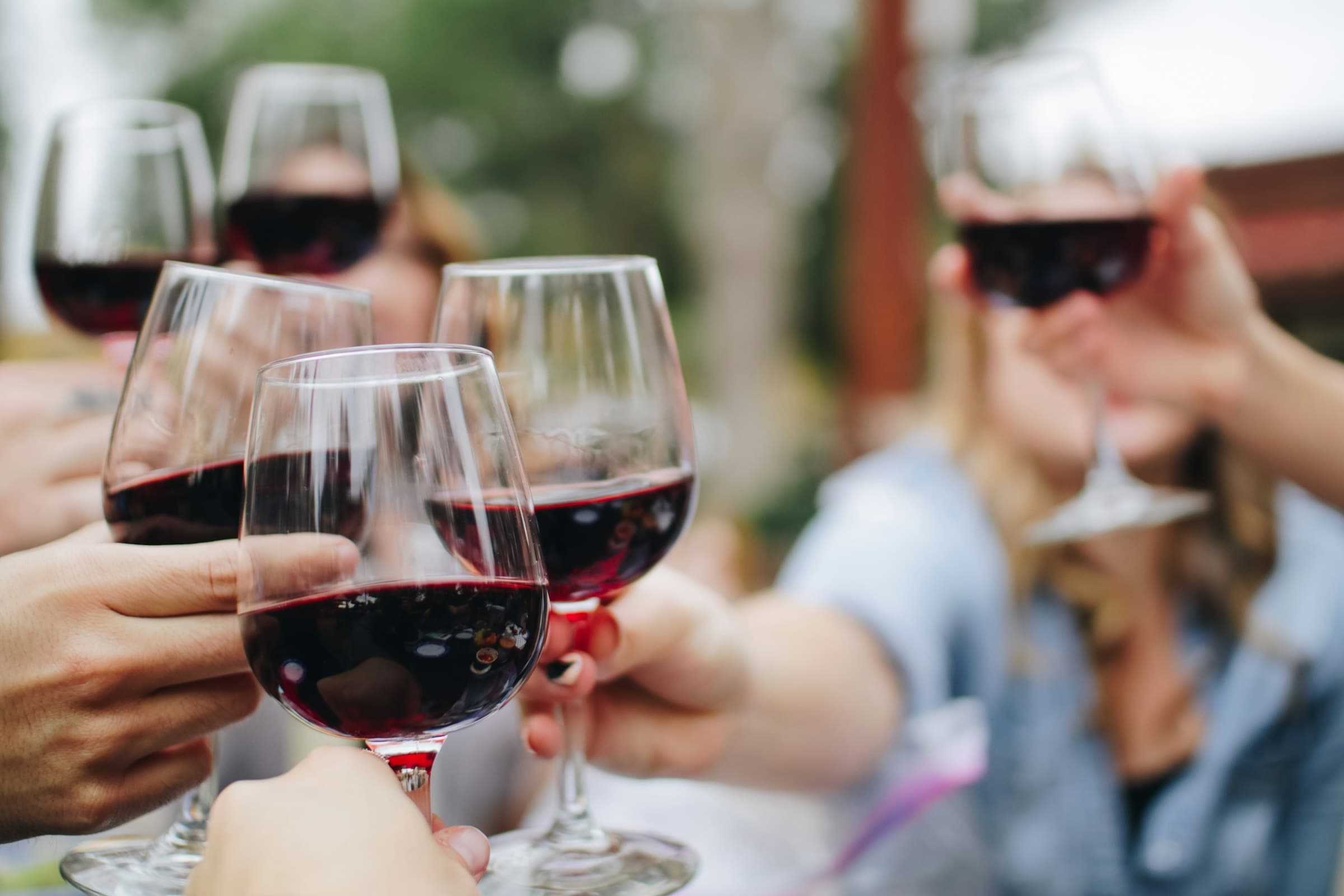 Friends raising glasses of red wine at an outdoor table