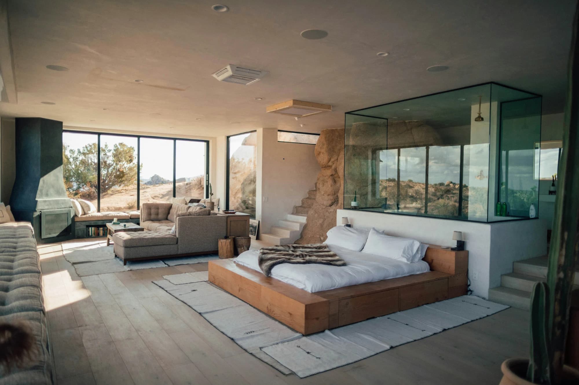 A light-filled desert suite with a platform bed and floor-to-ceiling windows over the landscape