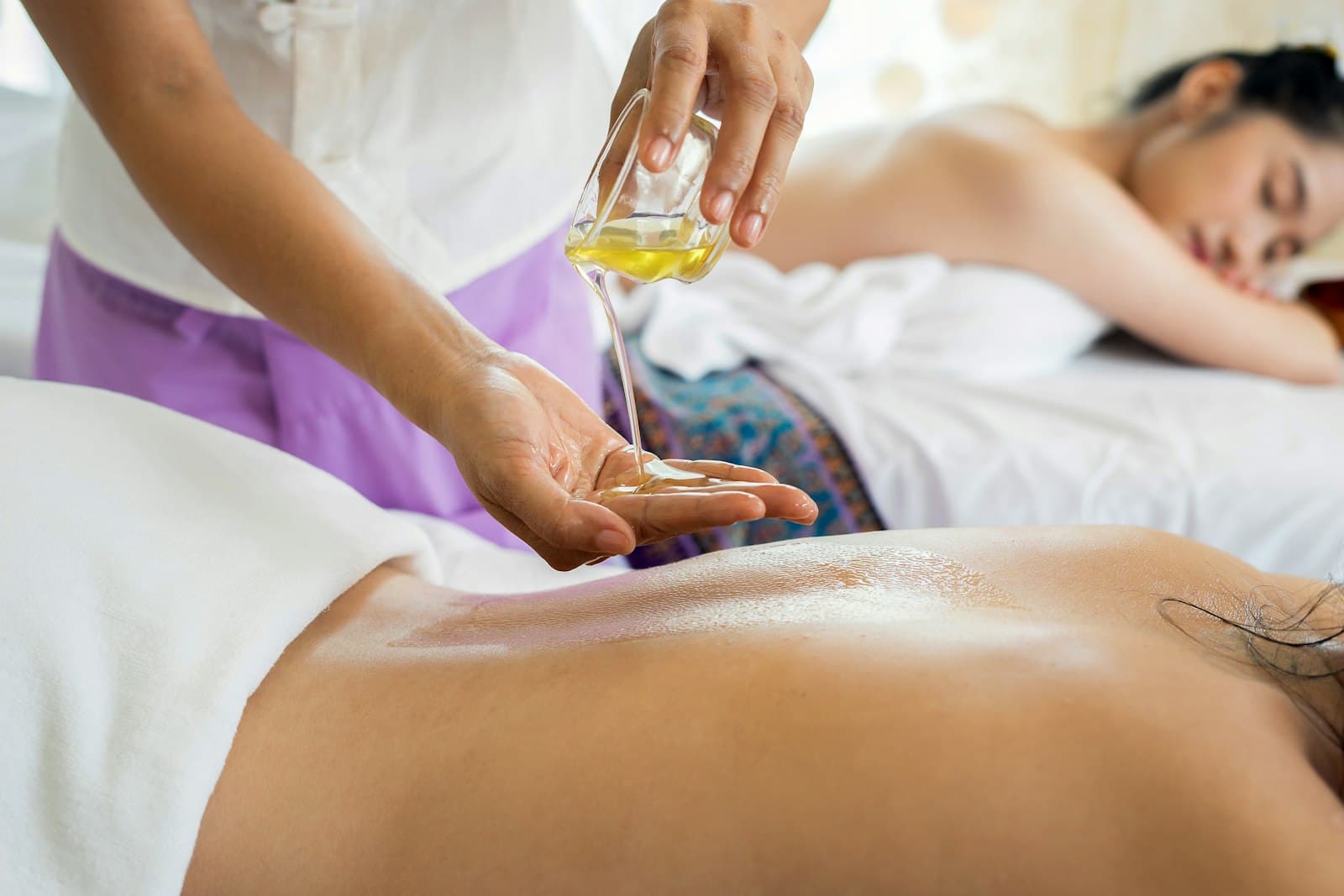 Warm oil poured into a therapist's hand before a massage