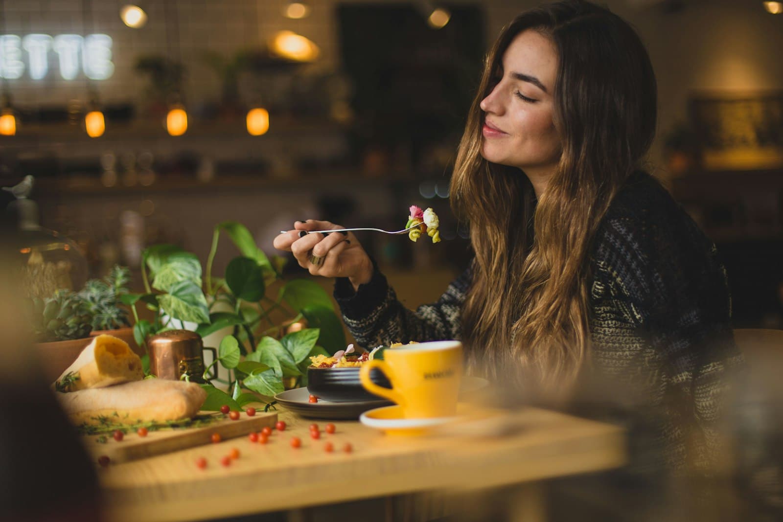 Woman savoring a dish in the warm light of a restaurant